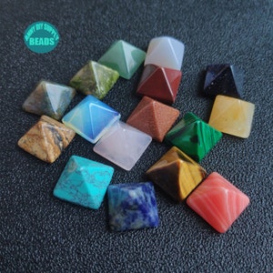 May include: A set of 14 small, pyramid-shaped crystals in various colours, including green, red, blue, yellow, brown, and white. The crystals are arranged in a circle on a black surface. The text "ANNY DIY SUPPLY BEADS" is visible in the top left corner of the image.