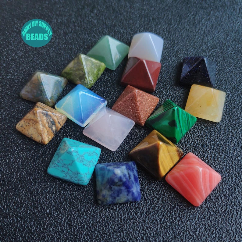 May include: A set of 14 small, pyramid-shaped crystals in various colours, including green, red, blue, yellow, brown, and white. The crystals are arranged in a circle on a black surface. The text "ANNY DIY SUPPLY BEADS" is visible in the top left corner of the image.