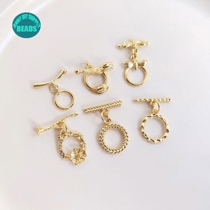 May include: Gold-toned metal toggle clasps with various designs, including a flower, a dragonfly, and a rope-like pattern. The clasps are perfect for adding a touch of elegance to jewelry projects.