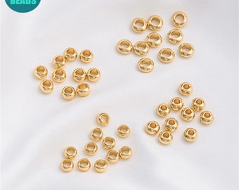 May include: Gold-colored metal beads scattered on a white surface. The beads are small, round, and have a hole through the center. The image includes a logo that says "ANNY DIY SUPPLY BEADS".