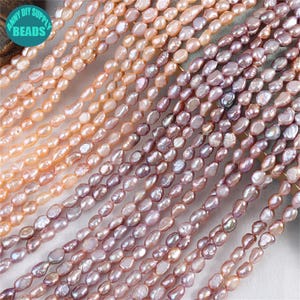 May include: Strands of freshwater pearls in shades of peach, pink, and lavender. The oval-shaped beads are strung together, creating a textured surface. The image includes the text "ANNY DIY SUPPLY BEADS" in a circular logo.
