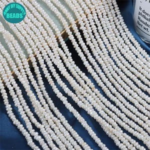May include: Multiple strands of white, irregular freshwater pearls. The pearls are strung together, creating a cascading effect. The image is well-lit, highlighting the natural lustre of the pearls. The beads are from Anny DIY Supply.