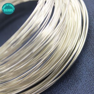 Peut inclure: Gros plan sur une bobine de fil de couleur argent&eacute;e, probablement pour la fabrication de bijoux ou l'artisanat. Le fil est &eacute;troitement enroul&eacute;, cr&eacute;ant un aspect dense et textur&eacute;. L'image est bien &eacute;clair&eacute;e, soulignant l'&eacute;clat m&eacute;tallique du fil. Le texte "ANNY DIY SUPPLY BEADS" est visible.