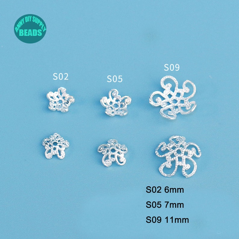 May include: Silver-colored flower-shaped beads in various designs and sizes. The beads are labeled S02 (6mm), S05 (7mm), and S09 (11mm). The image includes the text "Anny DIY Supply Beads" in a green circle.
