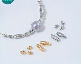 May include: Anny DIY Supply Beads logo in a teal circle. The image shows various metallic beads, including silver and gold oval and round beads. A strand of beads with a large pearl is also visible. The beads are on a white surface.