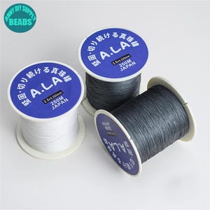 Puede incluir: Tres carretes de hilo de pesca gris y blanco. Los carretes est&aacute;n etiquetados "A.L.A.  2.5 x 0.265mm 200M JAP&Oacute;N" y "A.L.A. 2.0 x 0.235mm 200M JAP&Oacute;N".