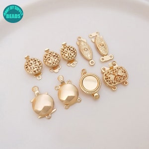May include: A set of ten gold-toned metal clasps for jewelry making. The clasps are in various shapes and sizes, including round, oval, and ornate designs.