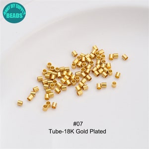May include: A close-up of a pile of gold-plated metal tube beads. The beads are small and round, and they are ideal for jewellery making. The image also includes the text "#07 Tube-18K Gold Plated".