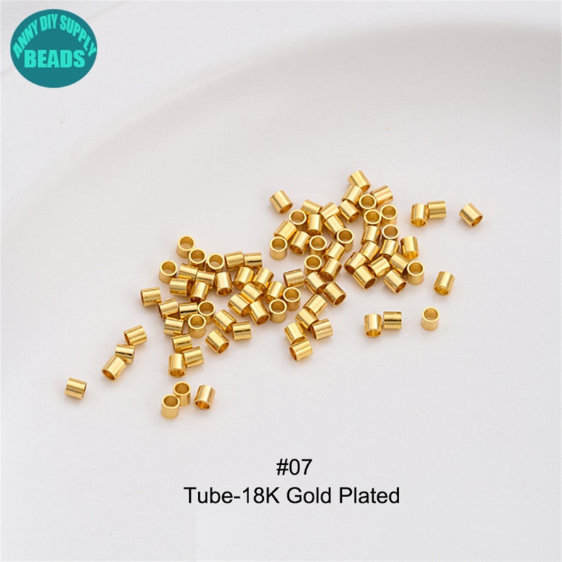 May include: A close-up of a pile of gold-plated metal tube beads. The beads are small and round, and they are ideal for jewellery making. The image also includes the text "#07 Tube-18K Gold Plated".