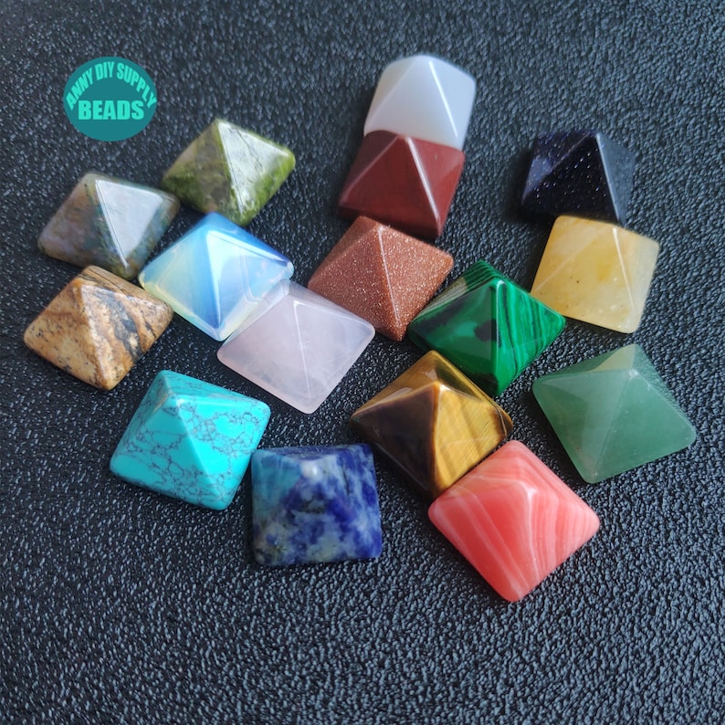 May include: Assortment of 15 small pyramid-shaped crystal stones in various colours, including green, blue, red, brown, yellow, white, and pink. The crystals are arranged on a black surface. "Anny DIY Supply Beads" is written in white text on a green circle.
