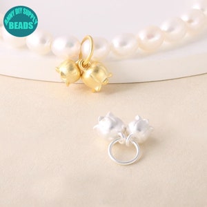 May include: Two gold-toned and two silver-toned flower charms with a loop for attaching to a necklace or bracelet. The charms are in the shape of a flower with a bell-like shape.