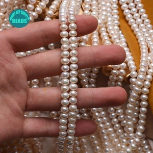 May include: A strand of white freshwater pearls, approximately 6-7mm in size, with a smooth, lustrous finish. The pearls are strung on a clear thread and are perfect for jewelry making.