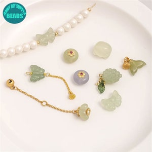 Può includere: Assortimento di ciondoli in giada verde a forma di farfalla, uva e foglia con accenti dorati. Sono inclusi anche perline rotonde in giada con accenti floreali e una collana di perle.