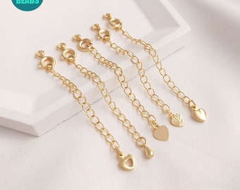 May include: Five gold chain extenders with lobster clasps and different charms, including a heart, a teardrop, and a sunburst design.