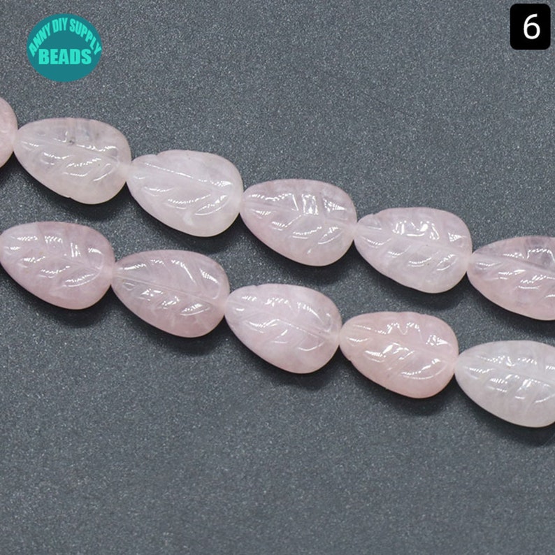 May include: A strand of pink rose quartz beads with a leaf design. The beads are smooth and polished.