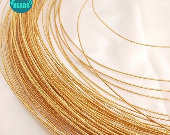 May include: A close-up of a spool of gold-colored wire with a sparkly finish. The wire is wound in a coil and is ready to be used for crafting projects.