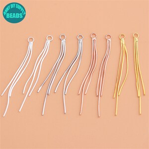 Può includere: Sei paia di orecchini pendenti con diverse finiture. Gli orecchini sono realizzati con sottili fili di metallo a forma di catena. Le finiture includono argento, oro e oro rosa.