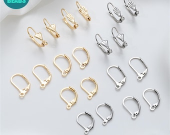 May include: An assortment of gold and silver-colored earring findings, including lever-back and hook styles. The findings are arranged on a white surface, showcasing various designs for jewelry making. The image includes the text "ANNY DIY SUPPLY BEADS" in a circular logo.