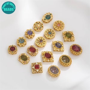 May include: Assortment of 18 gold-tone metal spacer beads with various coloured rhinestones. The beads feature different shapes, including round, oval, square, and flower designs.