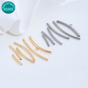 Peut inclure: Un assortiment de composants de bijoux en métal incurvés, de tons or et argent. Les pièces varient en taille et comprennent des tubes pleins et des tubes avec de petites boucles, adaptés à la fabrication de bijoux DIY. L'image comprend un logo turquoise qui dit "ANNY DIY SUPPLY BEADS".