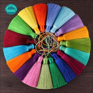 Puede incluir: Un conjunto de 18 borlas de seda de colores, dispuestas en círculo sobre una superficie de madera. Las borlas están hechas de tela suave y sedosa y tienen una variedad de colores, incluyendo rojo, naranja, amarillo, verde, azul, morado y rosa.