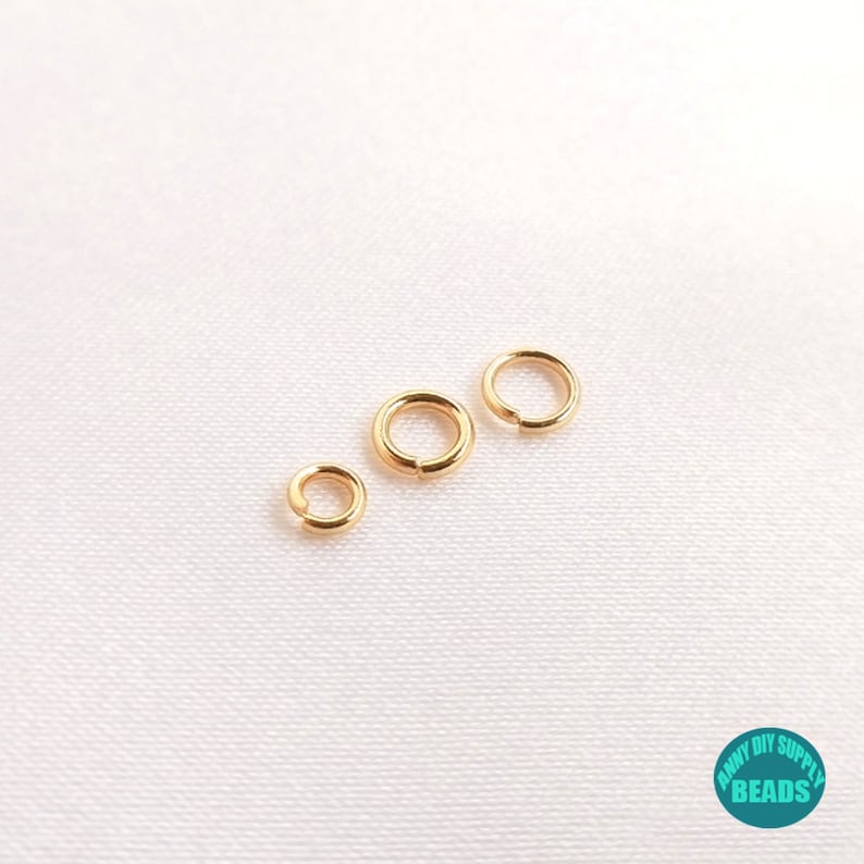 May include: Three gold jump rings of different sizes. The rings are smooth and shiny.