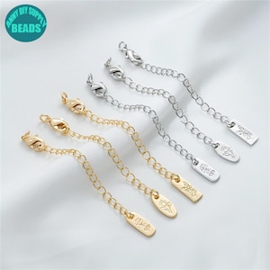 Pode incluir: Quatro correntes de extensão douradas e prateadas com fechos de lagosta e etiquetas decorativas. As etiquetas têm um design floral e o texto "Army DIY Supply Beads".