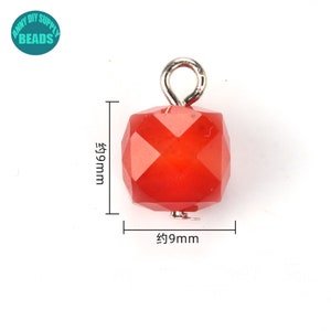 May include: Red faceted gemstone bead with a silver loop attached. The bead measures approximately 9mm in diameter.