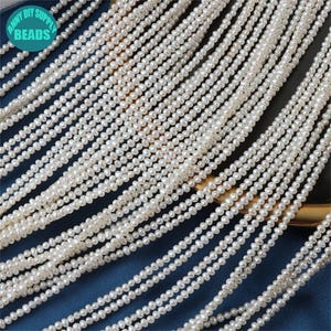 Pode incluir: Um fio de pérolas de água doce brancas, com aproximadamente 3-4 mm de tamanho, dispostas em filas. As pérolas são lisas e têm um brilho sutil. O fio é perfeito para fazer joias ou artesanato.