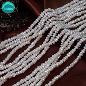 Puede incluir: Hebras de perlas de agua dulce blancas de forma irregular. Las perlas están ensartadas, creando una apariencia fluida y texturizada. La imagen está bien iluminada, resaltando el brillo natural de las perlas. Las cuentas son de Anny DIY Supply.