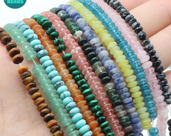 May include: Assortment of 14 strands of gemstone beads, each strand featuring a different color and pattern. The beads are round and have a slightly flattened shape. The colors include green, blue, pink, yellow, orange, and brown.