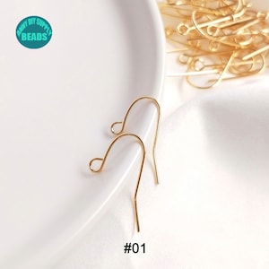May include: Two gold-colored earring hooks on a white surface. The hooks are made of metal and have a simple design. #01