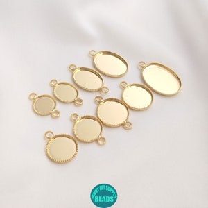 Op de afbeelding: Een set van acht ovale en ronde hangerbakjes van goudkleurig metaal met een parelrand. De bakjes hebben twee springringen aan de bovenkant om aan een ketting of koord te bevestigen.