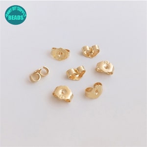 Può includere: Primo piano di sette dorsi di orecchini dorati. I dorsi sono in metallo e hanno diverse forme, tra cui cuore, rotondo e ovale. I dorsi sono progettati per essere utilizzati con orecchini a perno.