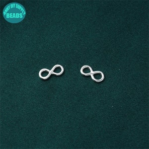 May include: Two silver infinity symbol charms on a green fabric background.