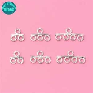 May include: Six silver-toned metal jewelry findings with multiple loops. The findings are designed to connect multiple strands of beads or chains.