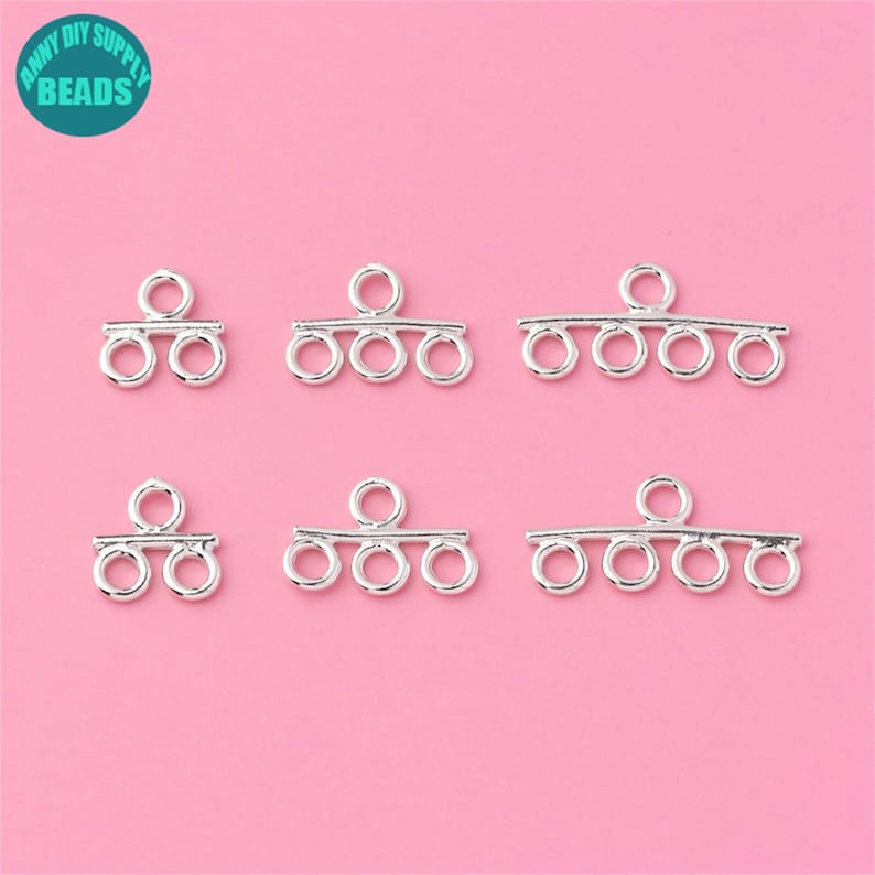May include: Six silver-toned metal jewelry findings with multiple loops. The findings are designed to connect multiple strands of beads or chains.
