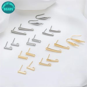 Puede incluir: Un conjunto de 14 hallazgos para pendientes en tonos dorados y plateados. Los hallazgos están hechos de metal y tienen un diseño simple y elegante. Son perfectos para hacer tus propios pendientes.