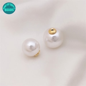 May include: Two white pearl beads with gold accents. The beads have a hole in the top for stringing.