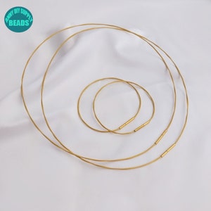 May include: Three gold-colored metal chains of different lengths, with a small, round, gold-colored metal clasp on each chain.