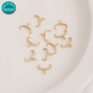Op de afbeelding: Een close-up van tien goudkleurige metalen kralencaps met een lus aan de bovenkant. De kralencaps zijn gerangschikt op een wit oppervlak.