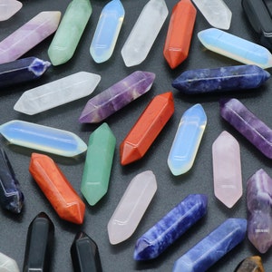 May include: A collection of various coloured crystal points, including red, green, blue, purple, and white. The points are arranged on a black surface.