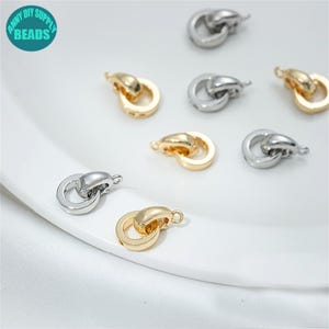May include: A close-up of gold and silver metal ring connectors. The connectors are in the shape of two interlocking circles. The connectors are used for jewelry making.