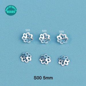 May include: Six silver-colored, flower-shaped bead caps with multiple holes, arranged on a light blue surface. The text "S00 5mm" is at the bottom. The top left corner has a logo that says "Anny DIY Supply Beads".
