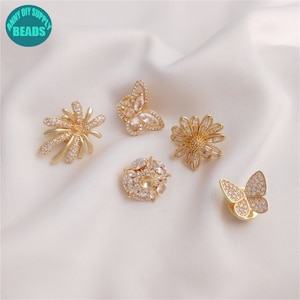Può includere: Cinque decorazioni in metallo dorato con accenti di cristallo trasparente. Le decorazioni includono un fiore, una farfalla e tre diversi stili di fiori rotondi.