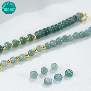May include: A strand of light green jade beads with gold spacers. The beads are round and smooth. There are also several loose beads in the image.