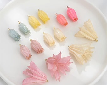 Peut inclure: Assortiment de breloques en résine de fleurs de couleur pastel avec des anneaux de saut dorés. Les breloques sont en forme de cloches et de lys.