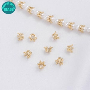 May include: Gold crown-shaped beads for jewelry making. The beads are small and have a delicate design.