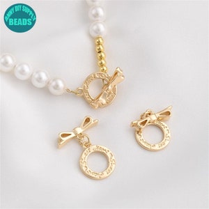 Puede incluir: Cierre de metal dorado con un diseño de lazo y las palabras "Heart & Soul" grabadas alrededor del círculo. El cierre es para la elaboración de joyas.