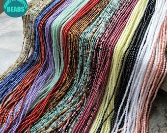 May include: A variety of gemstone beads in different colors, including blue, purple, green, red, brown, pink, white, and black. The beads are strung on a string and are arranged in rows. The beads are all approximately the same size and shape. The image is taken from a close-up perspective.
